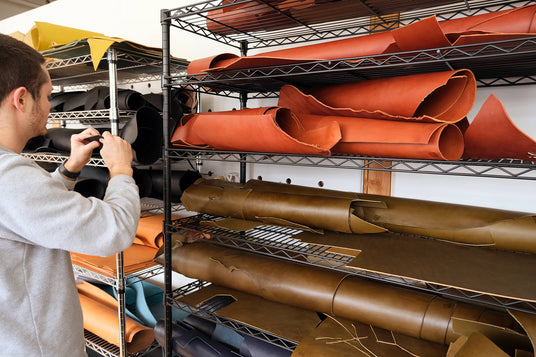 Cofounder Jake at the Portland Studio standing in front of a shelf with leather hides.