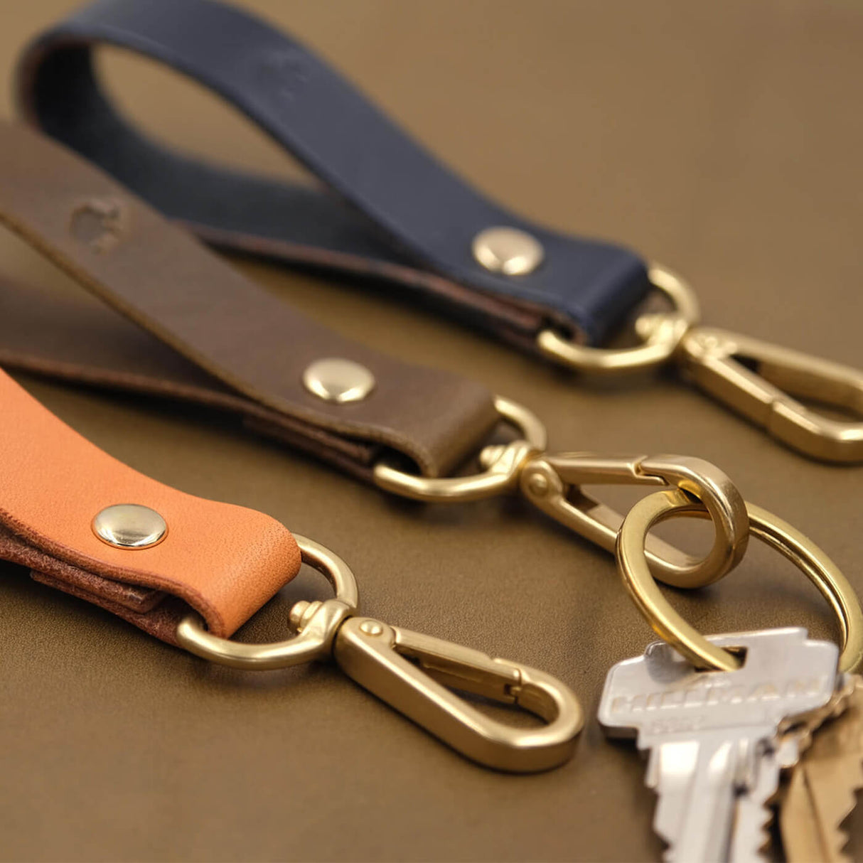 Tan, olive, navy leather Loop Keychains, hand-pressed Woolly Made logo, brass hardware, keys.