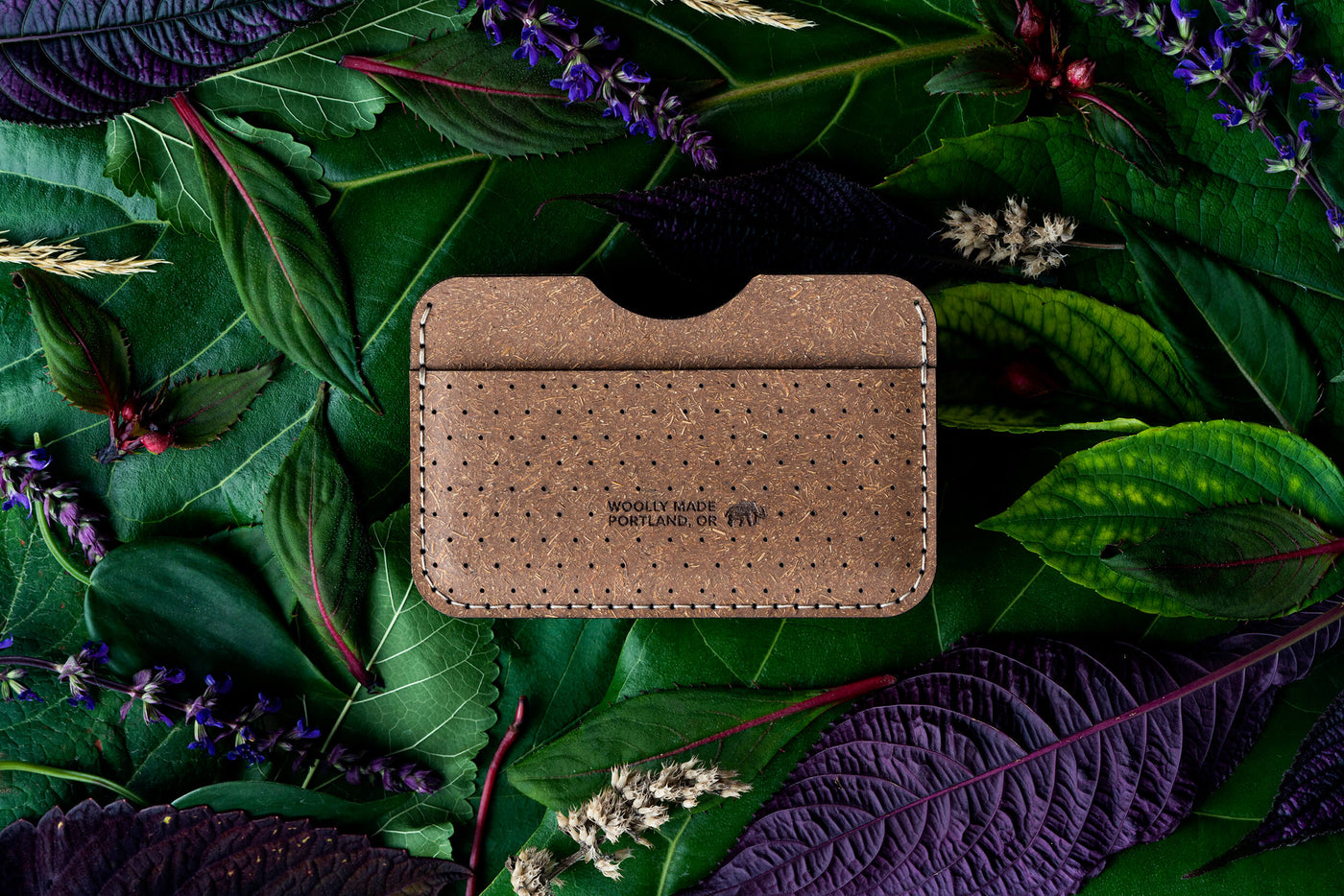 Top down view of the Plant Slim Wallet with decorative perforation and the Woolly Made logo on top of leaves and flowers.