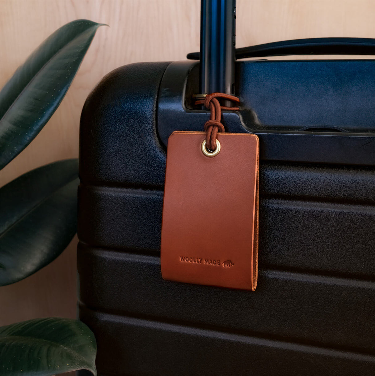 Woolly Made Standard Luggage Tag in Brown with elastic cord on a suitcase.
