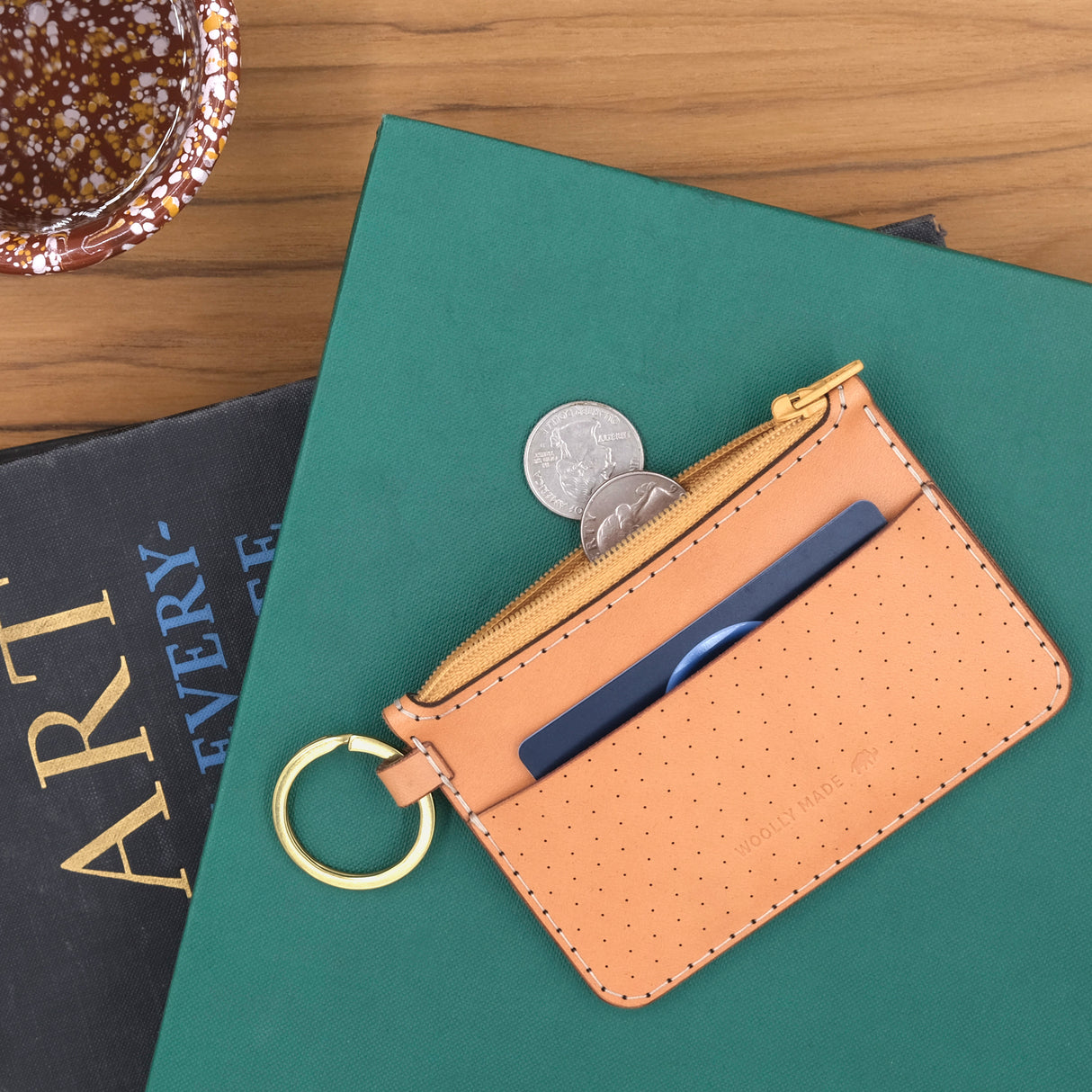 Woolly Made Zip Wallet in Tan. On a stack of books.