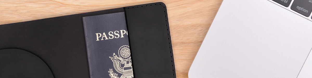 Black leather Passport Cover with passport next to Macbook pro.