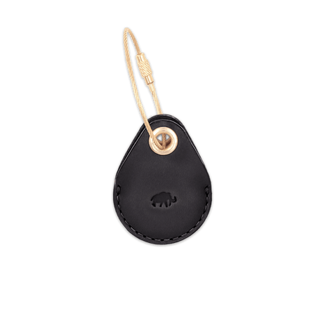 Black leather AirTag case with debossed Woolly Made logo and brass luggage loop.