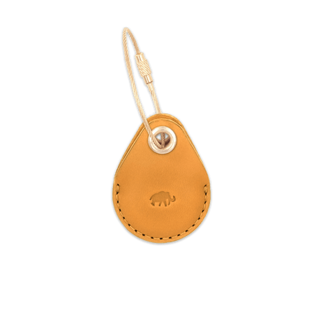 Gold leather AirTag case with debossed Woolly Made logo and brass hardware.