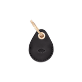 Black leather AirTag case with debossed Woolly Made logo and brass hardware.