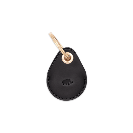 Black leather AirTag case with debossed Woolly Made logo and brass hardware.