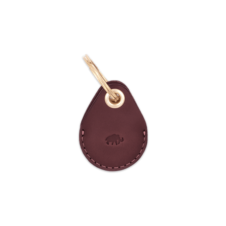 Burgundy leather AirTag case with debossed Woolly Made logo and brass hardware.