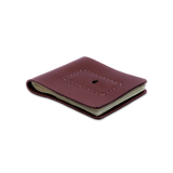 Burgundy leather Cash Magnet Wallet 3/4 angle view with folded bills and etched Woolly Made logo.