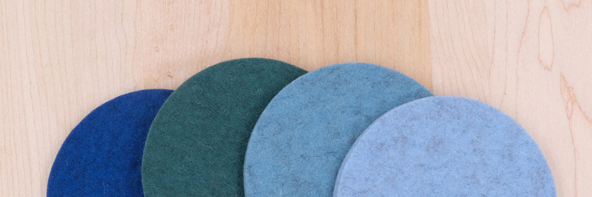 Cropped view of Cool Mix Woolsters set of four in royal blue, blue, teal, and sky blue spread out on a wood table.