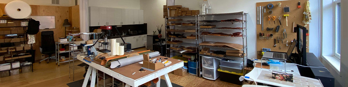 View of the Woolly Made Portland Studio with work benches, tools, shelves, leather hides, and a laser cutter.