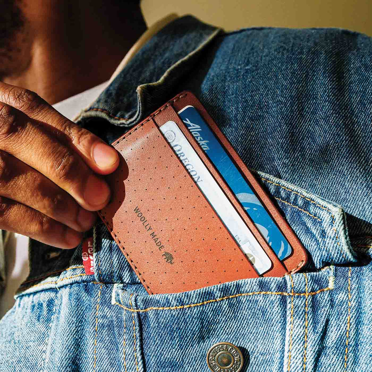 Brown Half Wallet coming out of a jacket pocket.