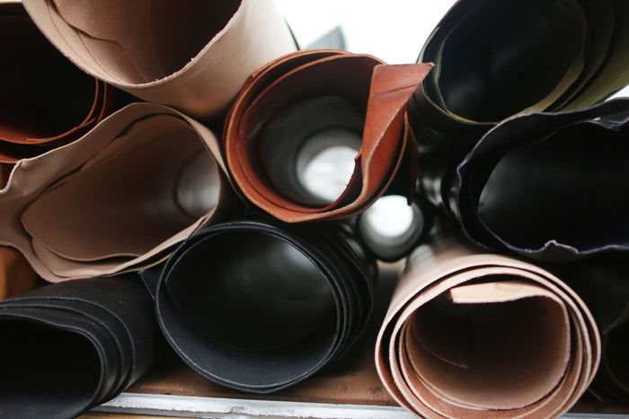 Rolls of leather hides stacked on a table.