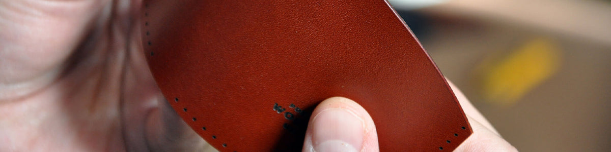 Hands folding a piece of a leather wallet.