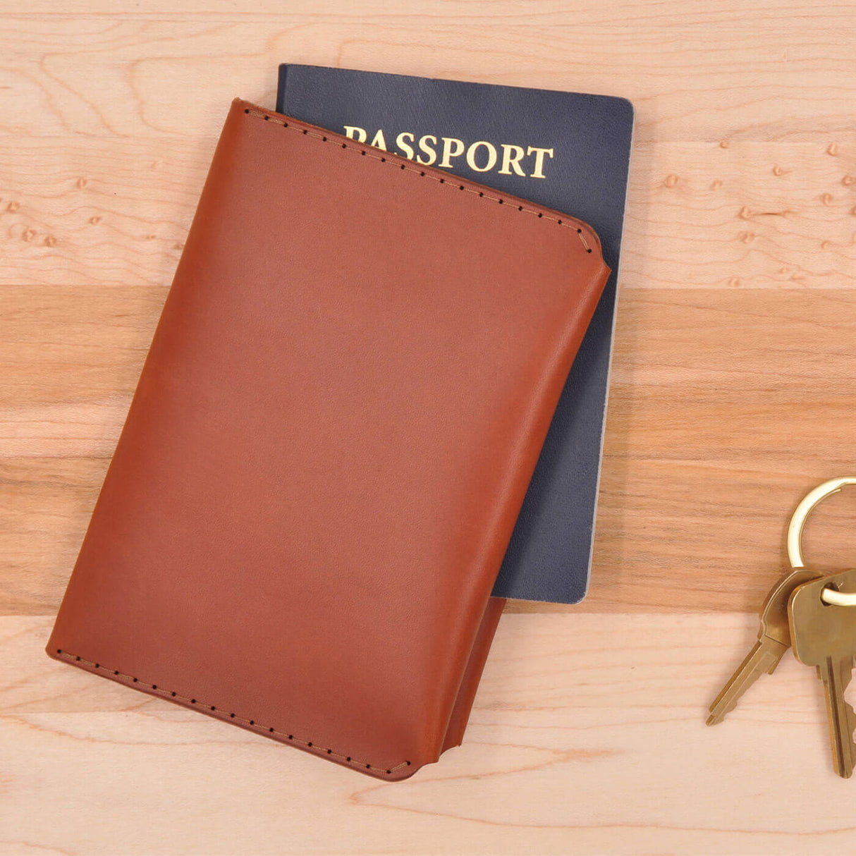 Brown leather Passport Wallet with passport next to a set of keys on a table.