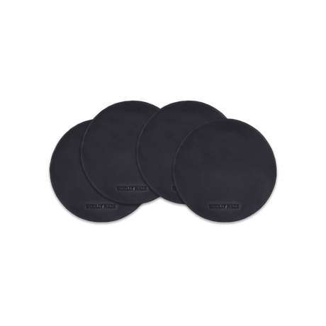 Black leather round coaster set with hand-pressed Woolly Made logo spread out.