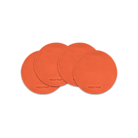 Orange leather round coaster set with hand-pressed Woolly Made logo spread out.