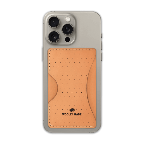 Tan leather Stick-On Wallet with decorative perforation and etched Woolly Made logo on iPhone.