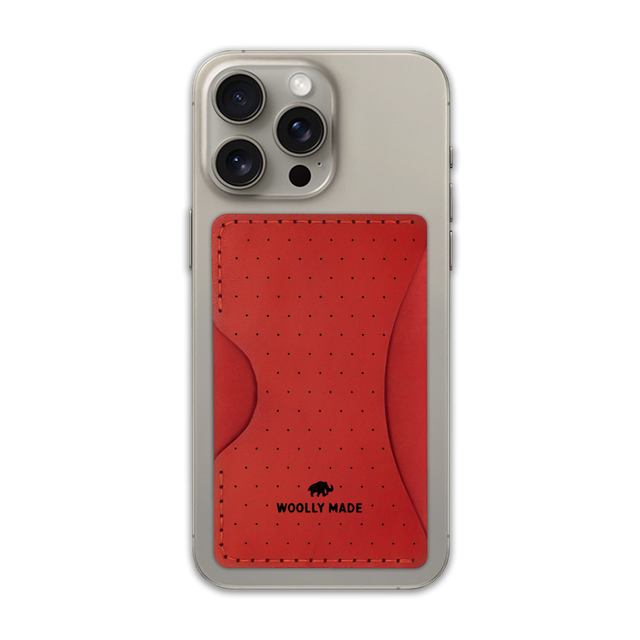 Red leather Stick-On Wallet with decorative perforation and etched Woolly Made logo on iPhone.