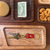 Woolly Made Red leather Swivel Keychain with Brass Hardware. The set is on a table with wooden trays strewn about with little everyday life things surrounding the keychain.