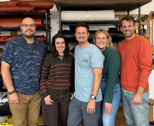 Five people standing together in a room with shelves of materials