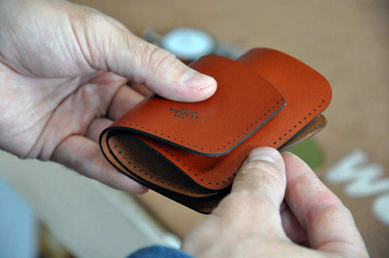 Hands assembling pieces for a leather wallet.